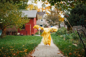 A child in long golden dress and wings leaps through garden