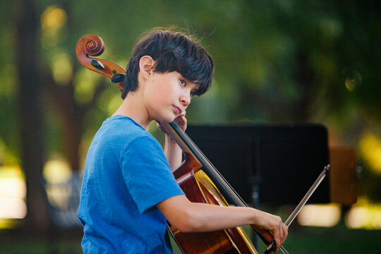 A beautiful boy plays cello in park