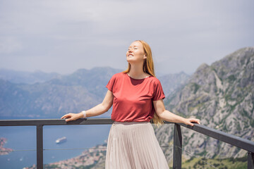 Woman tourist enjoys the view of Kotor. Montenegro. Bay of Kotor, Gulf of Kotor, Boka Kotorska and walled old city. Travel to Montenegro concept. Fortifications of Kotor is on UNESCO World Heritage
