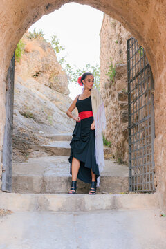 Woman in a flamenco dress at the entrance of an ancient castle