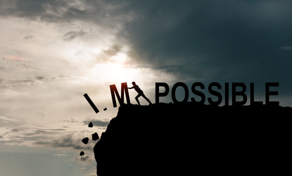 Businessman push impossible wording to possible wording on top of mountain with sunlight.