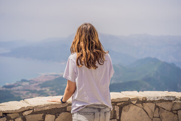 Naklejka premium Woman tourist enjoys the view of Kotor. Montenegro. Bay of Kotor, Gulf of Kotor, Boka Kotorska and walled old city. Travel to Montenegro concept. Fortifications of Kotor is on UNESCO World Heritage