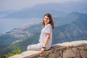 Naklejka premium Woman tourist enjoys the view of Kotor. Montenegro. Bay of Kotor, Gulf of Kotor, Boka Kotorska and walled old city. Travel to Montenegro concept. Fortifications of Kotor is on UNESCO World Heritage