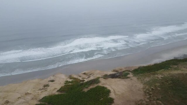 Aerial drone view of pacific coastline moving back into green mountain gliderport during a foggy morning, Torrey Pines State Natural Reserve, San Diego, California
