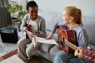 High angle portrait of two young woman playing guitars together and composing song music