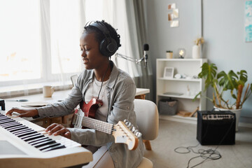 Minimal portrait of young black woman playing synthesizer and composing music at home, copy space