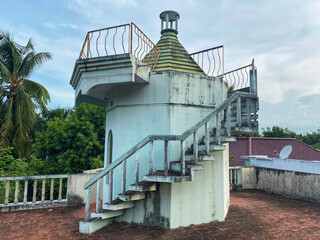 Elevated structure on a terrace serving as a viewpoint at an old countryside house - spiral staircase with handrails. Blue Green colour - Coconut trees, blue sky and scenic background 