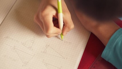 School boy doing math homework at the table
