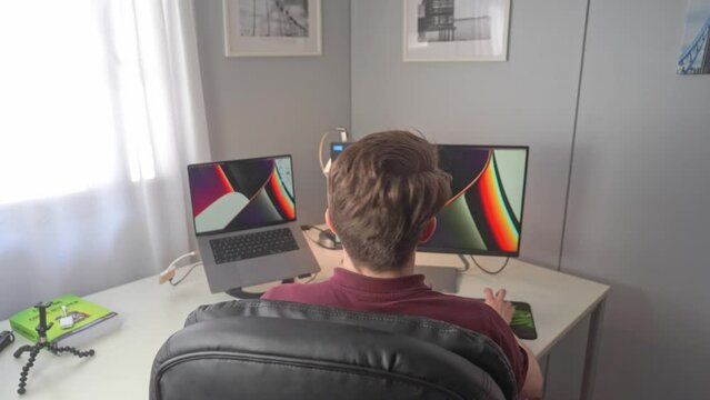 A young man eagerly steps into a scene with a computer workstation and begins work on creating a new program for his influence website and social media accounts