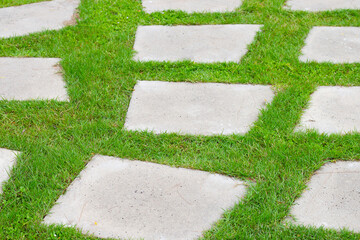 Stone path on green grass in garden