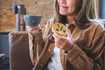 Closeup image of a young woman holding coffee cup and a piece of cookie