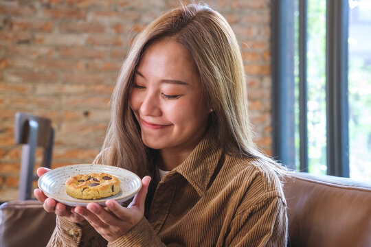 Portrait image of a beautiful young asian woman holding and showing a piece of cookie