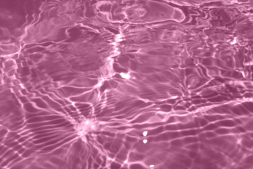 Defocus blurred transparent pink colored clear calm water surface texture with splash, bubble. Shining pink water ripple background. Surface of water in swimming pool. Pink bubble water shining.