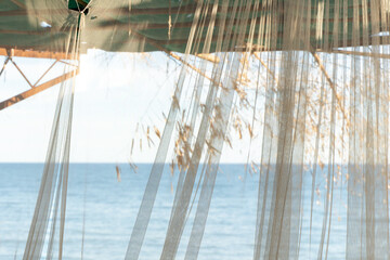 Bamboo gazebo on the seashore or ocean on the beach with a transparent curtain in summer