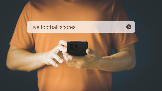 Football fan checking mobile phone gor live football scores in his home. Searching Browsing Internet Data Information with search bar. Search Engine technology networking Concept. - Powered by Adobe