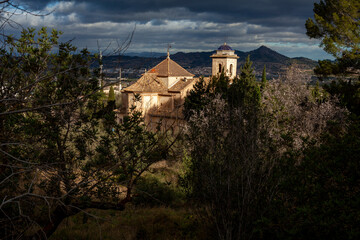 Fototapeta premium sun rays hitting old town chapel in the forest with cloudy sky background