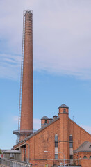 Tall red brick chimney and ventilations towers on a brick factory building an autumn afternoon day in Stockholm