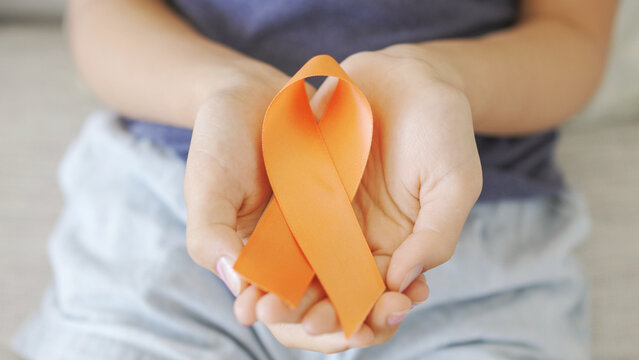 hands holding orange Ribbons, Leukemia cancer and Multiple sclerosis, COPD and ADHD awareness, world kidney day