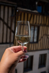 Tasting of white grand cru classe chablis wine with old French houses on background, Burgundy, France