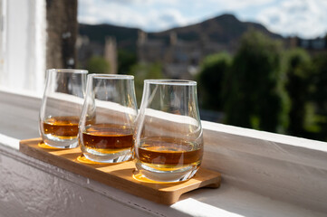Flight of single malt scotch whisky served on old window sill in Scottisch house with view on old part of Edinburgh, Scotland, UK