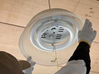 帽子をかぶり丸型蛍光灯を取り換える手元