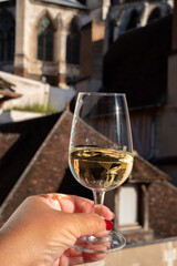 Tasting of white grand cru classe chablis wine with old French houses on background, Burgundy, France