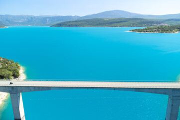 Fototapeta premium Aerial view on blue lake Sainte-Croix-du-Verdon, road bridge and cliffs, tourists destination in France
