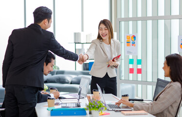 Millennial Asian professional successful young cheerful female  businesswoman in formal suit holding tablet computer shaking hands greeting with unrecognizable male businessman in company office