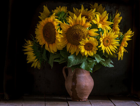 beautiful yellow Sunflower still life bouquet  in a clay jug ceramic rustic style oil honey Dark photo background wooden table Vintage. Retro. low key Autumn flowers.