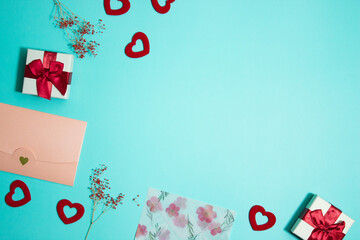 Pink envelope and red hearts, flowers and gift box over the mint background. 