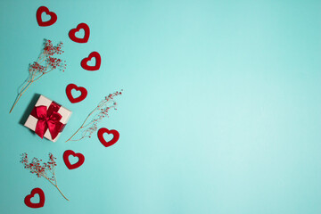 Red hearts and gift box and flowers over the mint background. 