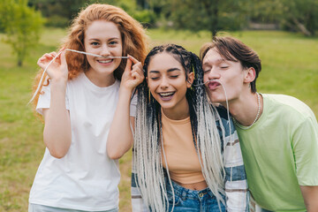 Group of multi-ethnic teen friends posing with funny facial expressions outdoors and sincerely smiling at camera. Outdoor lifestyle. Youth lifestyle. College