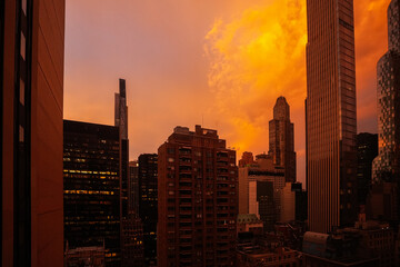 Amazing sunrise photographed between the tall skyscraper buildings from Manhattan, New York, with vivid orange sky color.