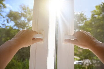 hands open a window with a magnificent landscape view of nature on a summer sunny day.