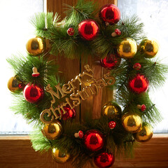 Fototapeta na wymiar christmas wreath with red and gold balls on a wooden window