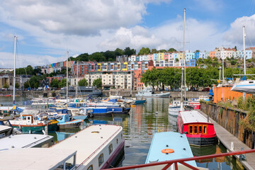 Bright, colourful riverboat houses moored on the river with beautiful coloured terrace houses in...