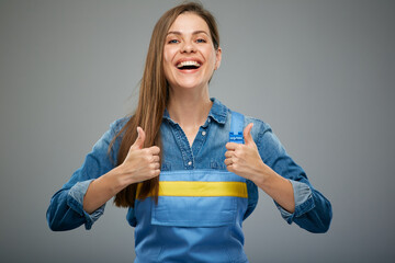 Smiling woman in blue overalls showing thumbs up. Isolated female portrait in builder worker...
