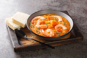 Healthy organic pumpkin cream soup with shrimps, sesame seeds and thyme close-up on a wooden tray on the table. Horizontal