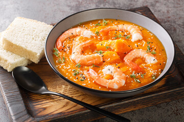 Pumpkin vegetable soup with shrimps, sesame seeds and thyme close-up on a wooden tray on the table. Horizontal