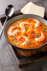 spicy pumpkin and shrimp soup with sesame and thyme closeup in the bowl on the table. Vertical