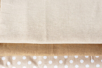 Fototapeta premium Natural linen raw organic cotton fabric. natural fabrics of ivory color - linen and cotton are stacked in a pile lie on a white background close-up