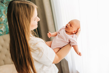 Mom with her baby newborn infant kid child at home take care in the bedroom put on clothes. Woman family women's health and maternity