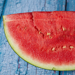 Red juicy watermelon slice with seeds on a blue background