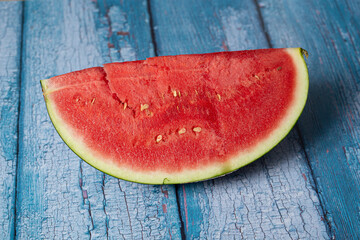 Fototapeta na wymiar Red juicy watermelon slice with seeds on a blue background