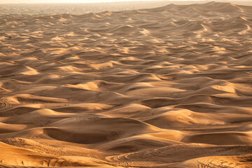 View of sand dunes criss crossed with vehicle tracks Dubai