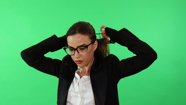 Sexy businesswoman with glasses and business suit arrange her hair with ponytail and gets ready for work day in office wearing punching gloves