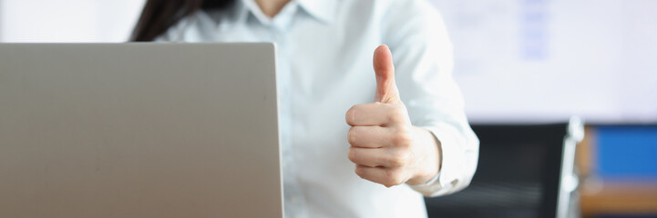 Office clerk showing thumbs up gesture working on laptop