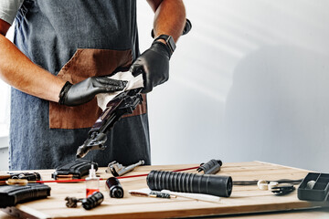 Close up of a man in apron wiping his firearm with a cloth