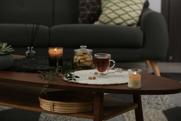 Tea, cookies and decorative elements on wooden table in living room