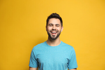 Young man laughing on yellow background. Funny joke